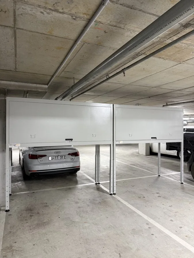 Two closed Kookaburra storage units installed above neighbouring car park bays, with a car parked underneath one of them